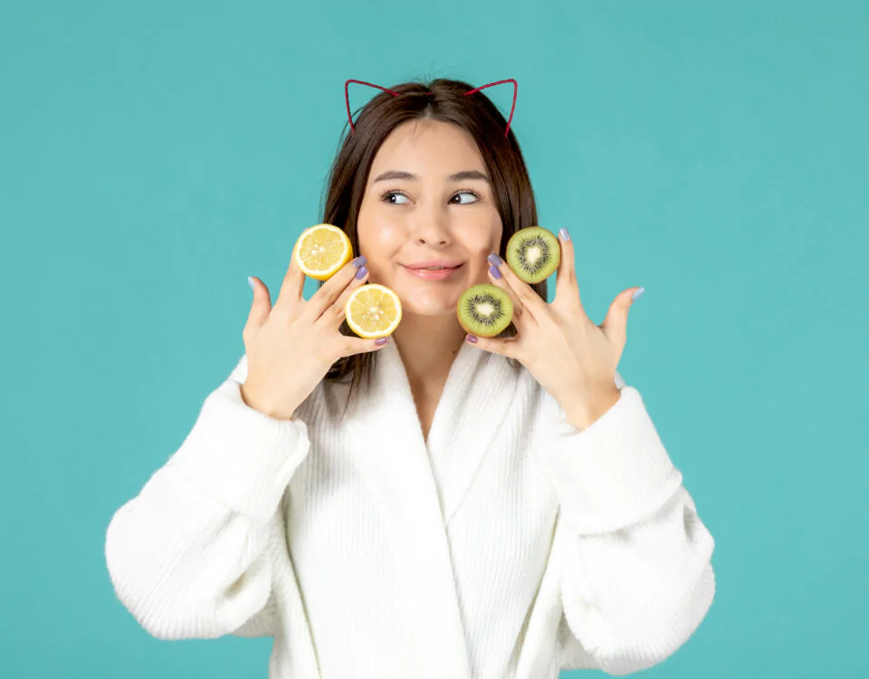 Front View Young Female Bathrobe Holding Sliced Lemons Kiwis Blue Background 960x750 1